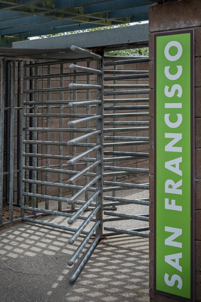 services-02 A metal turnstile entrance in San Francisco with a bright green sign.
